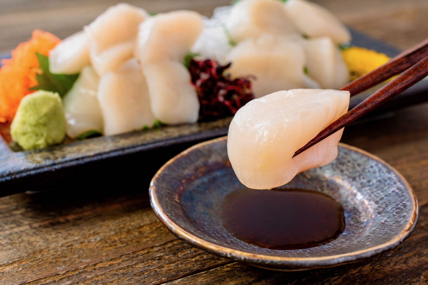 北海道産ホタテ貝柱の刺身,肉厚なホタテの刺身を醤油につける